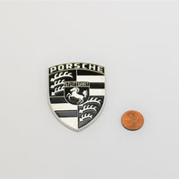 A Porsche emblem badge on top of spider for Porsche 928s.